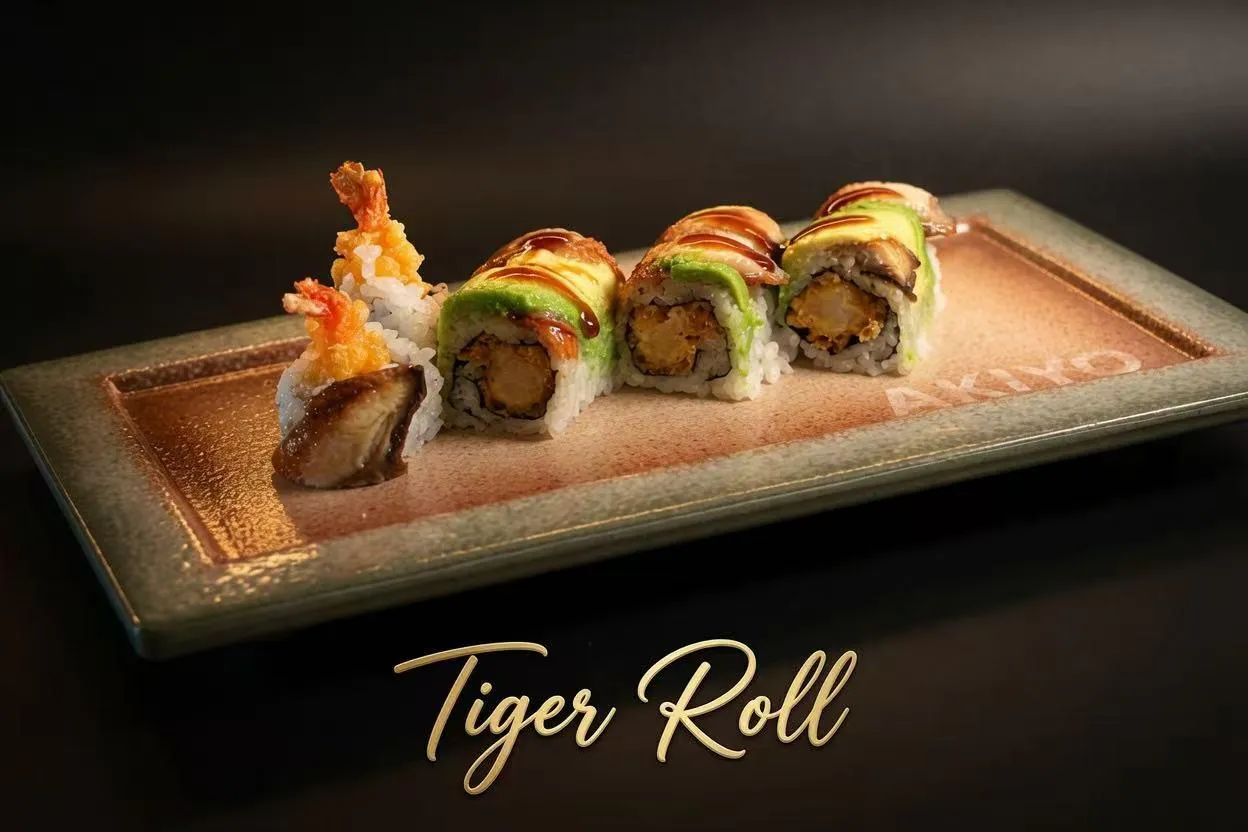 Tiger sushi roll with tempura shrimp, avocado, eel and teriyaki drizzle on branded rectangular plate with gold script text at Akiyo, a Japanese Restaurant in Johnson City